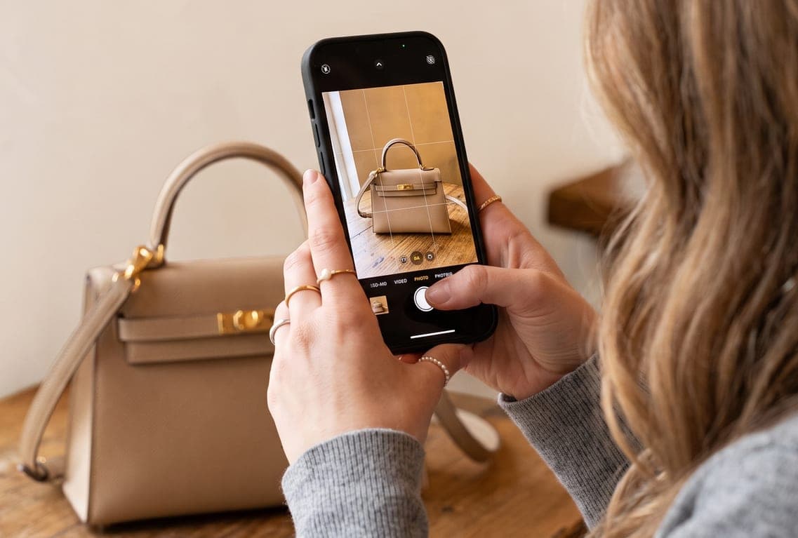 A client photographing a Hermès Kelly bag with her phone for authentication
