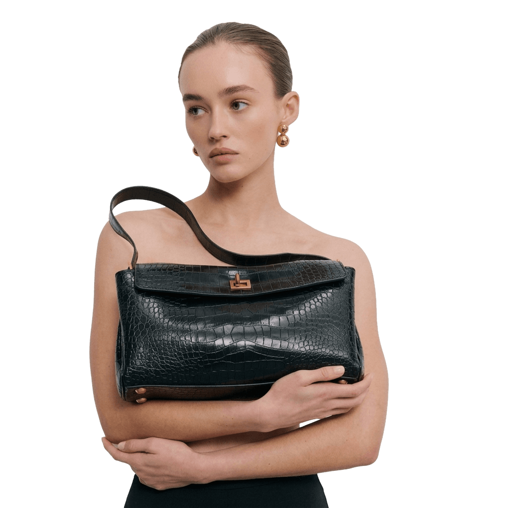 Model holding a black croc-embossed shoulder bag